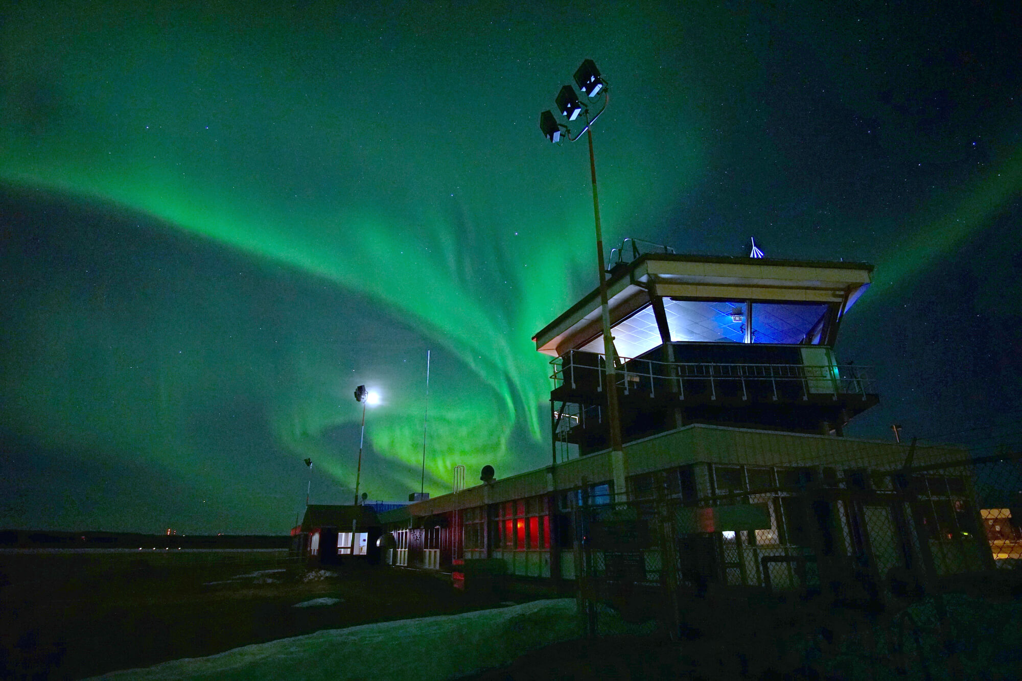 The northern lights illuminate the night sky above a building.